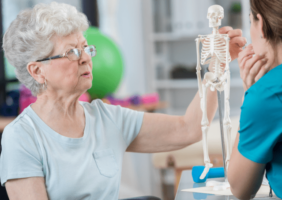 Elderly woman with nurse looking at a miniature skeleton