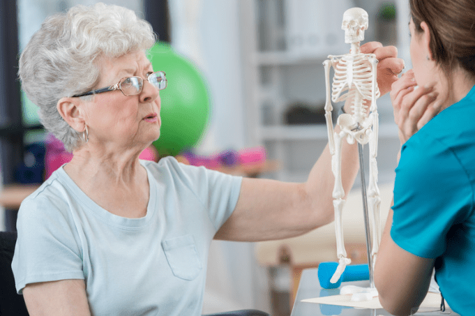 Elderly woman with nurse looking at a miniature skeleton