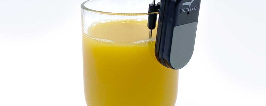 Uccello Liquid Level Indicator on the lip of a glass of orange juice