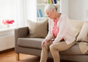 Elderly woman on the couch holding her knee