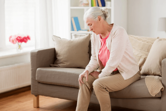 Elderly woman on the couch holding her knee