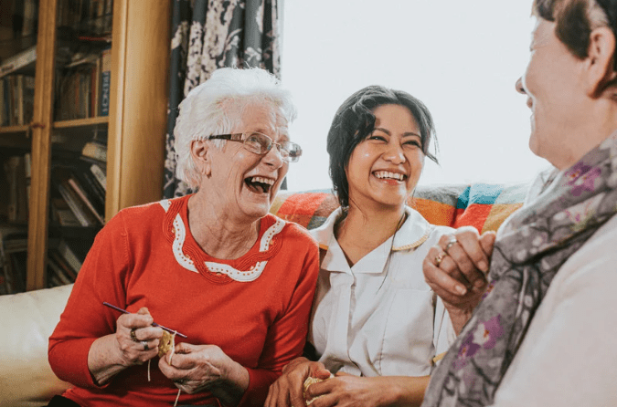 Elderly woman laughing with carer and friend