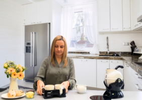 Woman in the kitchen using the Muggi Cup Holder carrying 2 cups of tea