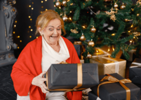 Elderly Woman Opening Chrismtas Presents Beside the Christmas Tree