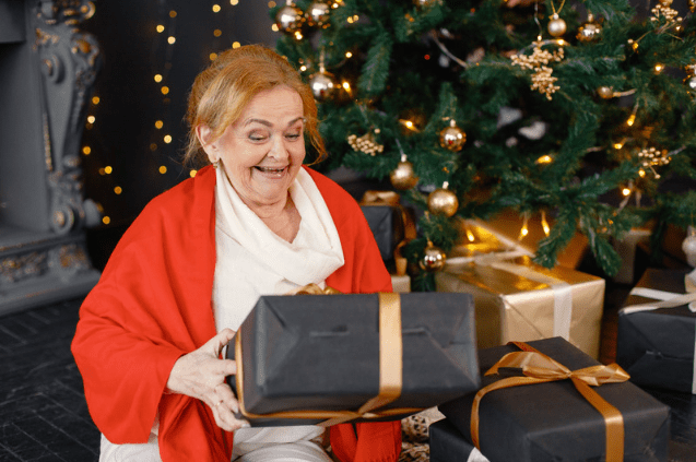 Elderly Woman Opening Chrismtas Presents Beside the Christmas Tree