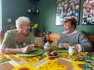 Mother and daughter in the dining room enjoying tea, biscuits and a chat