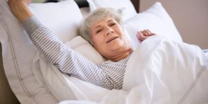 Elderly woman stretching in her bed