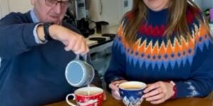 Elderly father and daughter enjoying a cup of tea together with festive Christmas jumpers on